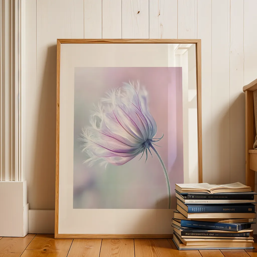 Framed pastel print of a fluffy purple and white flower against a white wooden wall, with a stack of books on the wooden floor.
