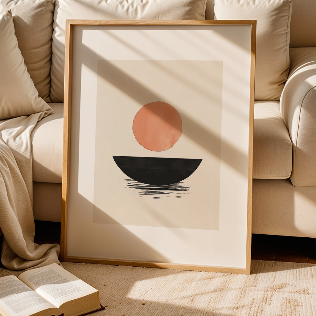Framed Japandi print leaning against a cream couch, with an open book on a rug in the foreground, bathed in sunlight.